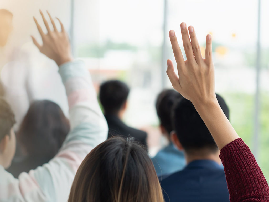 "Person raising their hand in a classroom setting."