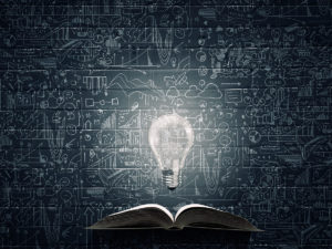 "Illustration of a light bulb glowing above an open book, with chalkboard sketches in the background."