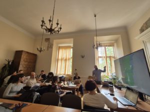 A gathering of people in a room, sitting around a table, actively participating in a discussion.