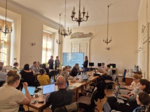 Several individuals gathered around tables in a spacious room, participating in discussions and collaborative work.