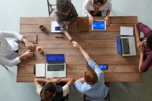 Several individuals seated at a table, focused on their laptops while engaging in a collaborative work session.